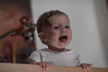 Image showing cute little one year old baby and making first steps in bed