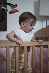 Image showing cute little one year old baby and making first steps in bed