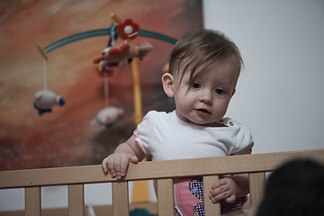 Image showing cute little one year old baby and making first steps in bed