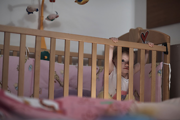 Image showing cute little one year old baby and making first steps in bed