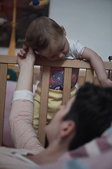 Image showing cute little one year old baby and making first steps in bed