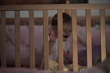 Image showing cute little one year old baby and making first steps in bed