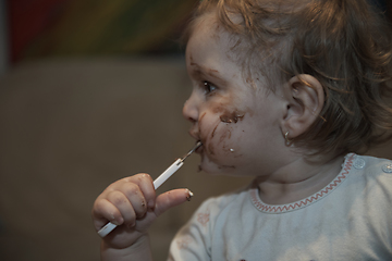 Image showing baby girl eating her chocolate desert with a spoon and making a mess