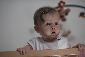 Image showing cute little one year old baby and making first steps in bed