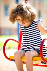 Image showing Young happy girl is swinging in playground