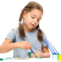 Image showing Little girl is painting with gouache