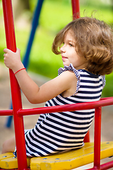 Image showing Young happy girl is swinging in playground