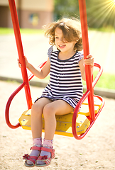 Image showing Young happy girl is swinging in playground