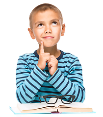 Image showing Young boy is daydreaming while reading book