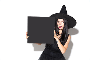 Image showing Young woman in hat and dress as a witch on white background