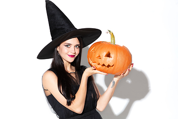 Image showing Young woman in hat and dress as a witch on white background