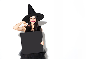 Image showing Young woman in hat and dress as a witch on white background