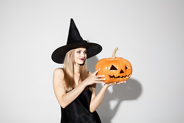 Image showing Young woman in hat as a witch on white background