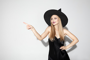 Image showing Young woman in hat as a witch on white background