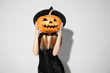 Image showing Young woman in hat as a witch on white background