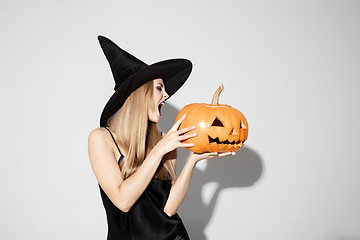 Image showing Young woman in hat as a witch on white background