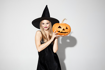 Image showing Young woman in hat as a witch on white background