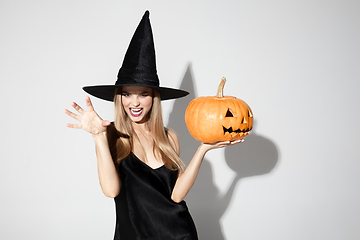 Image showing Young woman in hat as a witch on white background