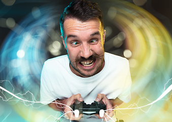 Image showing Enthusiastic gamer. Joyful young man holding a video game controller