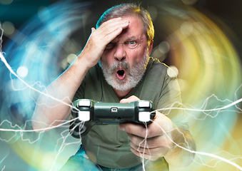 Image showing Enthusiastic gamer. Joyful man holding a video game controller