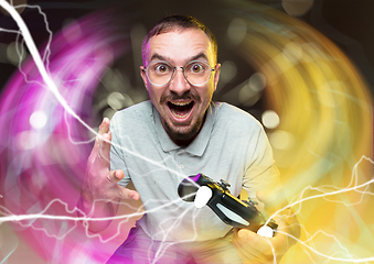 Image showing Enthusiastic gamer. Joyful young man holding a video game controller