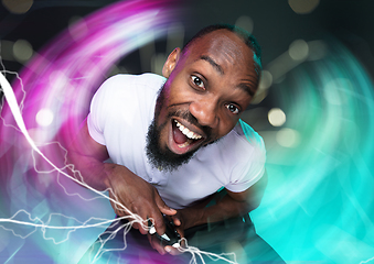 Image showing Enthusiastic gamer. Joyful young man holding a video game controller