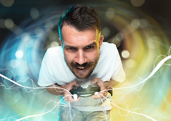 Image showing Enthusiastic gamer. Joyful young man holding a video game controller