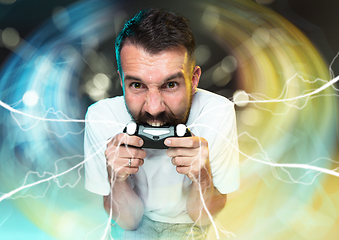 Image showing Enthusiastic gamer. Joyful young man holding a video game controller