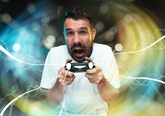 Image showing Enthusiastic gamer. Joyful young man holding a video game controller