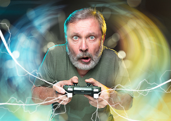 Image showing Enthusiastic gamer. Joyful man holding a video game controller