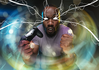 Image showing Enthusiastic gamer. Joyful young man holding a video game controller