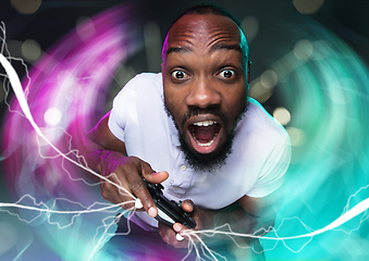 Image showing Enthusiastic gamer. Joyful young man holding a video game controller