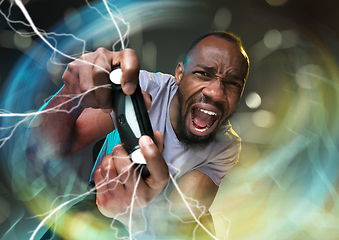 Image showing Enthusiastic gamer. Joyful young man holding a video game controller