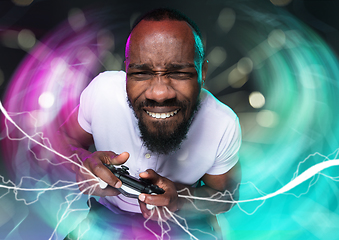 Image showing Enthusiastic gamer. Joyful young man holding a video game controller