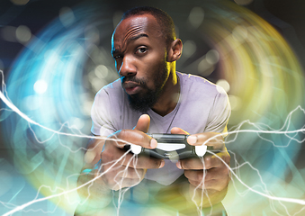 Image showing Enthusiastic gamer. Joyful young man holding a video game controller