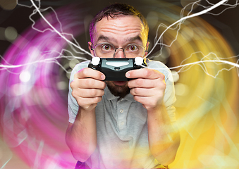 Image showing Enthusiastic gamer. Joyful young man holding a video game controller