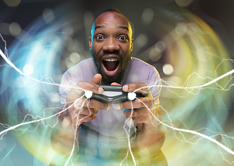 Image showing Enthusiastic gamer. Joyful young man holding a video game controller