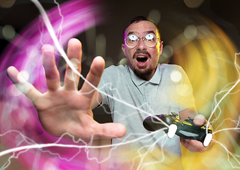 Image showing Enthusiastic gamer. Joyful young man holding a video game controller