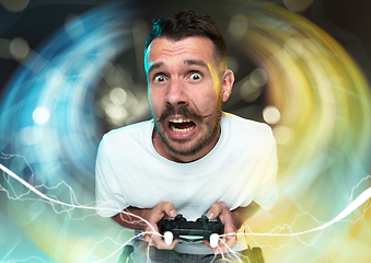 Image showing Enthusiastic gamer. Joyful young man holding a video game controller