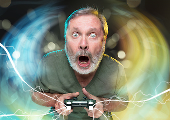 Image showing Enthusiastic gamer. Joyful man holding a video game controller