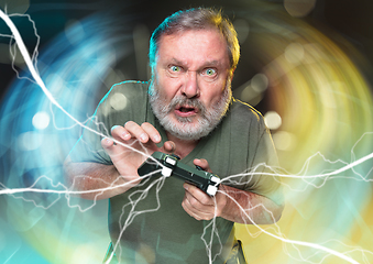 Image showing Enthusiastic gamer. Joyful man holding a video game controller