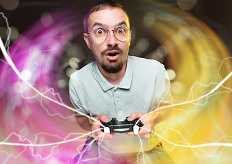 Image showing Enthusiastic gamer. Joyful young man holding a video game controller