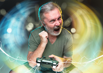 Image showing Enthusiastic gamer. Joyful man holding a video game controller