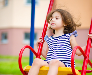 Image showing Young happy girl is swinging in playground