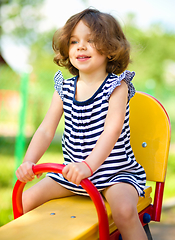 Image showing Young happy girl is swinging in playground