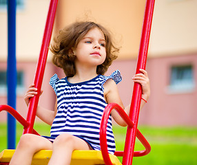 Image showing Young happy girl is swinging in playground