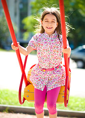 Image showing Young happy girl is swinging in playground