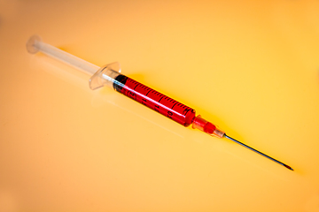 Image showing Syringe with blood on orange background