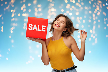 Image showing happy woman posing with sale sign over lights