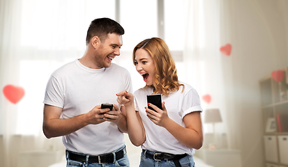 Image showing happy couple in white t-shirts with smartphones